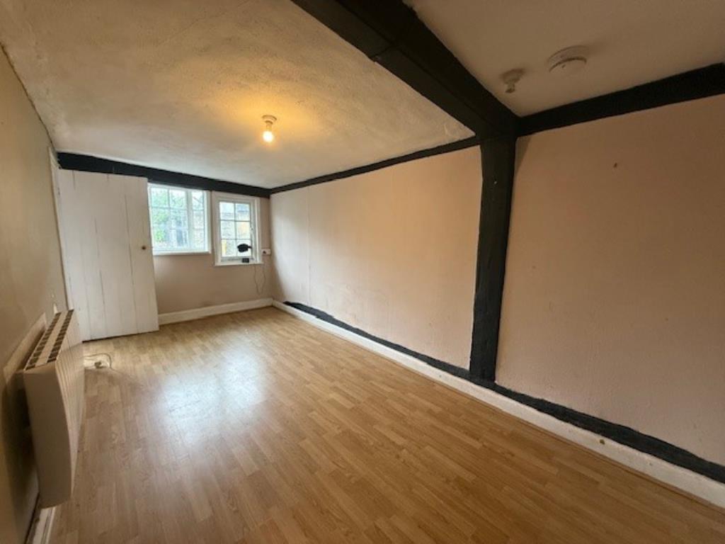 Lot: 168 - A PAIR OF THATCHED COTTAGES IN NEED OF IMPROVEMENT - 50 Abbey Street lounge with window and beams across ceiling